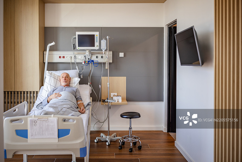 老年人在现代医院病房接受护理，周围有医疗设备和支持性工作人员。图片素材