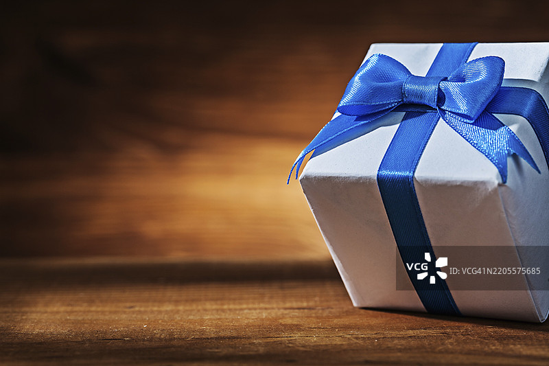 复古木材上的白色礼品盒和蓝色丝带图片素材