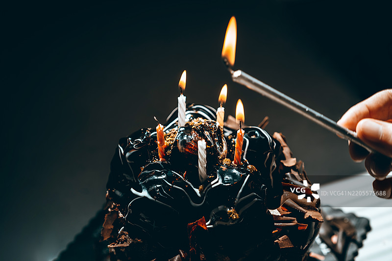 在巧克力蛋糕上点燃蜡烛庆祝图片素材