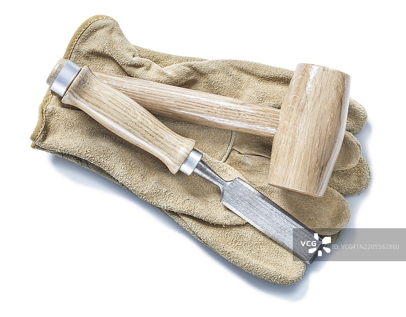 木槌和凿子放在白色背景的皮手套上图片素材