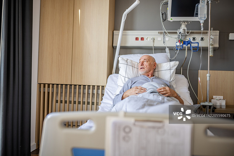 老年男子在医院病床上康复，接受现代医疗设施中医务人员的护理图片素材