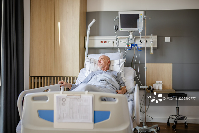 老年男子在现代医疗设施的病床上休息，接受护理。图片素材