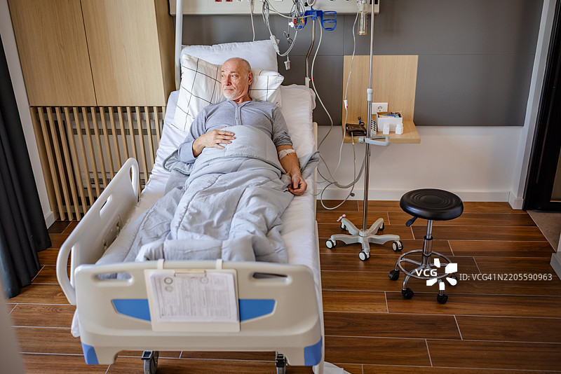 老年男子在现代医疗设施的病床上休息，接受医护人员的照顾图片素材