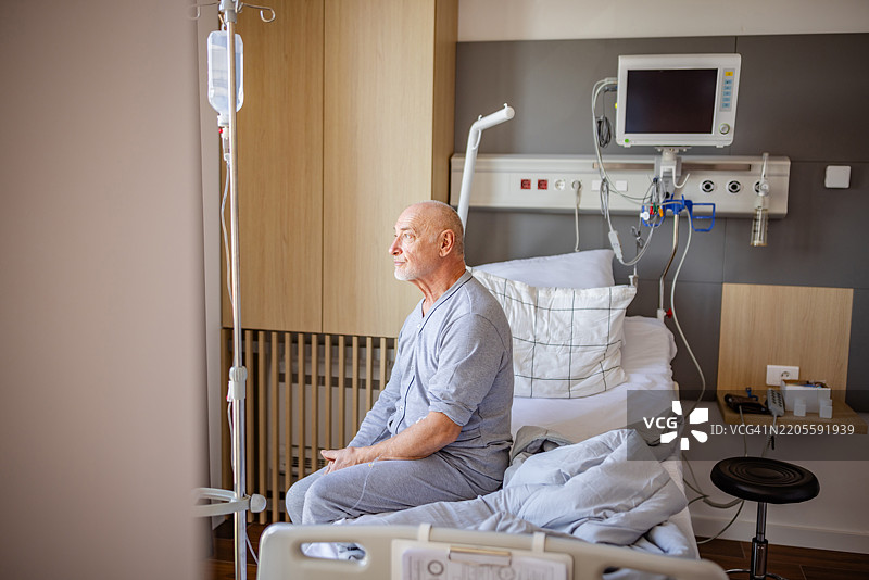 老年男子坐在恢复区的医院病床上，接受医务人员的照顾和支持。图片素材