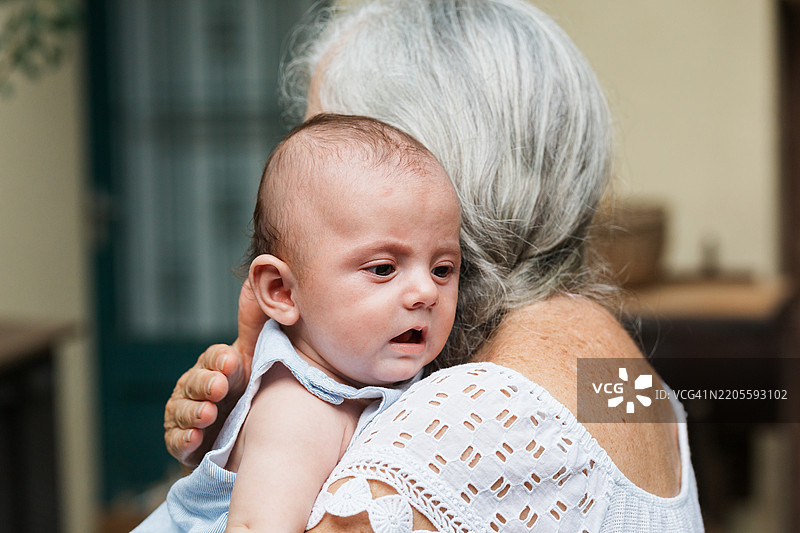 奶奶在给五个月大的宝宝打嗝，宝宝刚喝完奶。图片素材