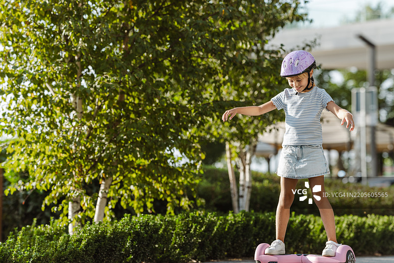 年轻女孩在阳光明媚的夏日公园里骑滑板车图片素材