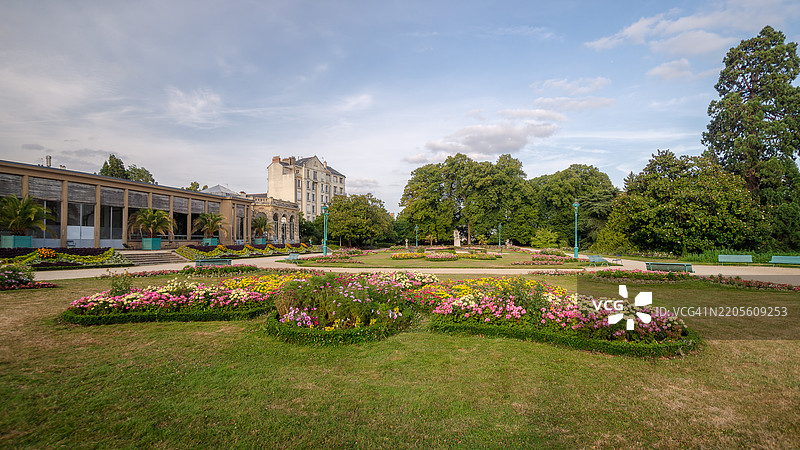 日落时分，法国雷恩的塔博尔公园著名景观花园的法式花园、前温室和橘子园建筑的广角视图，前景是草坪和花坛。图片素材
