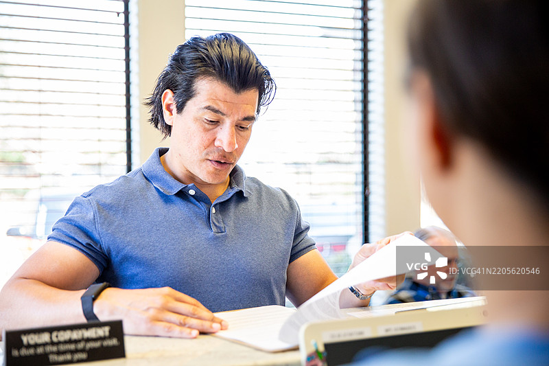 西班牙裔男子在医院候诊室前台办理登记图片素材