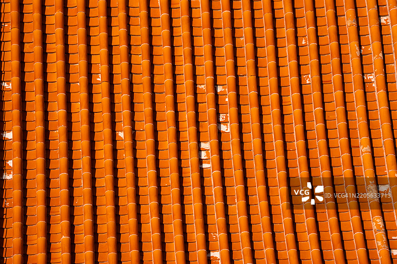 红色粘土屋顶瓦的特写。橙色背景。图片素材