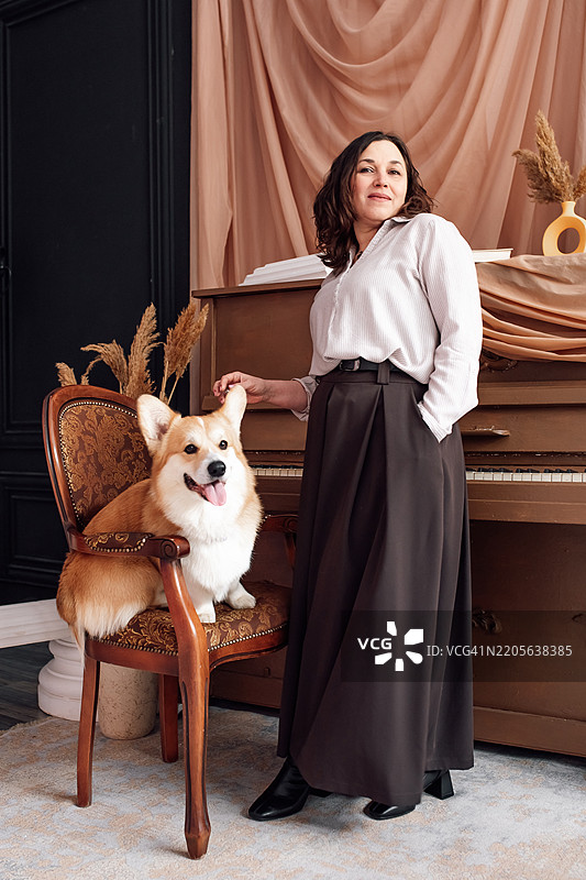 优雅的女性与柯基犬在时尚的室内环境中图片素材