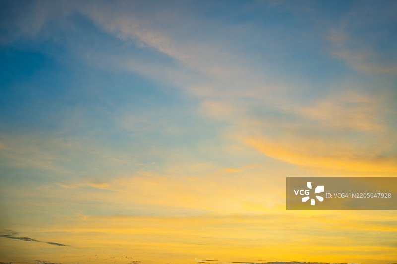 充满活力的日落天空，温暖的色调混合着黄色和蓝色图片素材