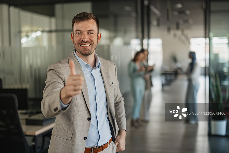 微笑的专业人士在办公室竖起大拇指图片素材