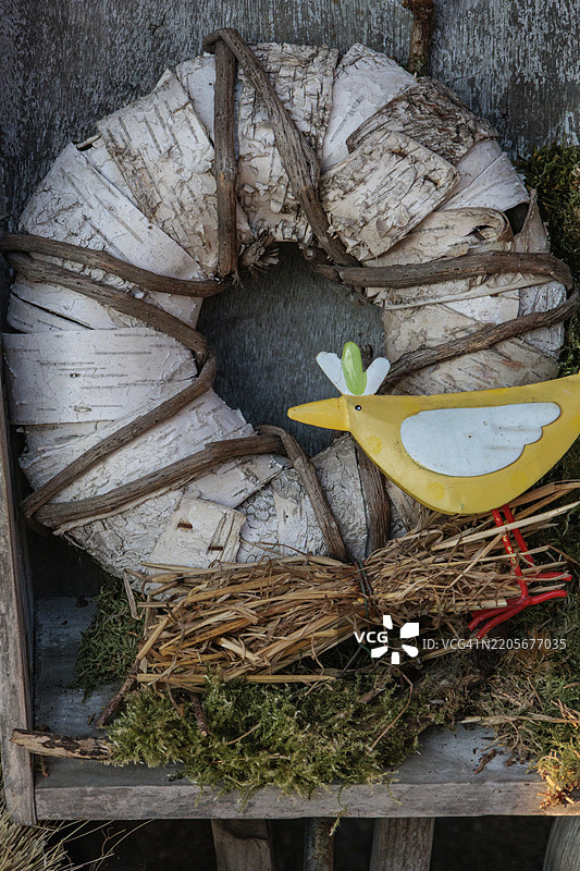 一个带有黄色小鸟和苔藓上的鸟巢的乡村风格木质花环，德国明斯特地区博尔肯，欧洲图片素材