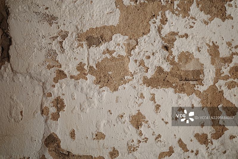 老旧的墙壁上白色灰泥剥落，露出了粗糙的棕色砖石。图片素材