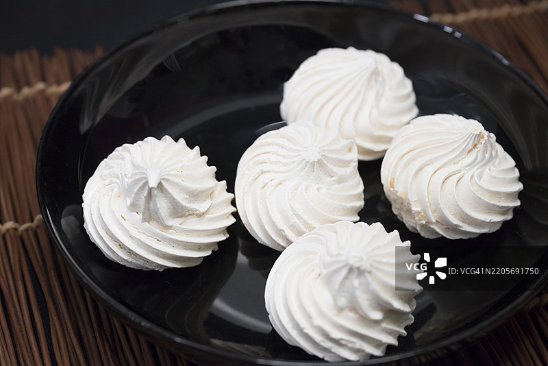 黑色盘子上的蛋白霜饼干图片素材