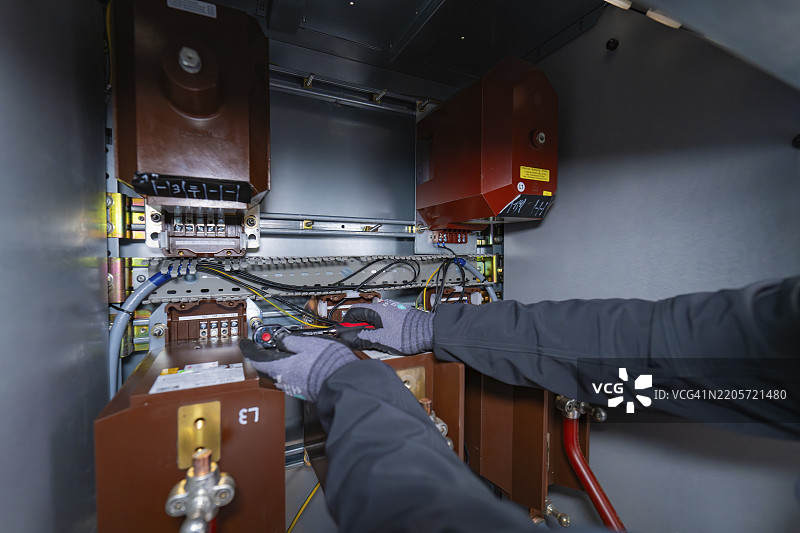技术人员戴着手套和工具在开关箱内进行布线，开关柜施工，光伏系统施工，主要客户，恩茨克赖斯，德国，欧洲图片素材