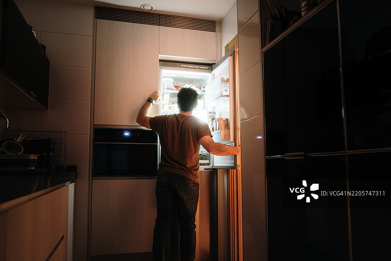 男人在夜晚打开冰箱图片素材