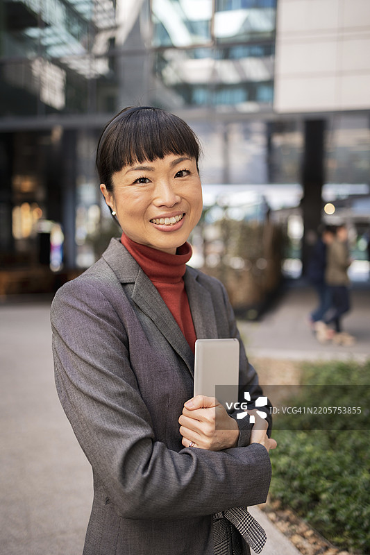 自信的女商人在现代城市环境中使用平板电脑图片素材
