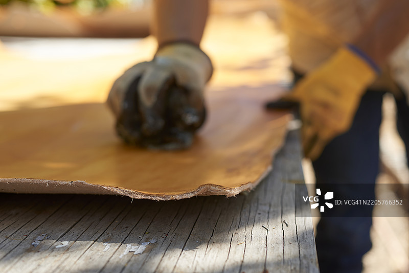 熟练的工匠使用传统方法为鞣制皮革染色，展示精细的手工艺和悠久的皮革工艺专长图片素材