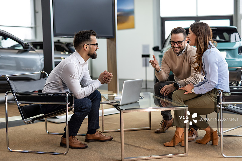 汽车销售员在汽车经销商处向一对夫妇展示车辆图片素材
