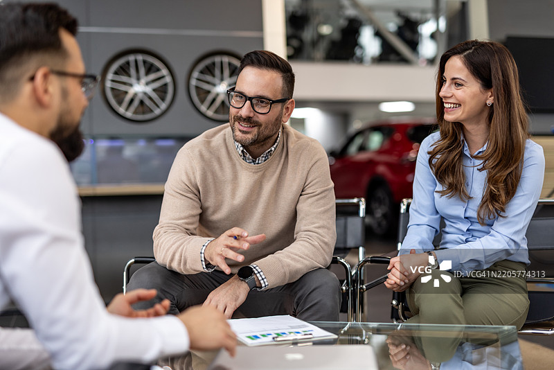 夫妇在汽车经销商处与销售员讨论图片素材