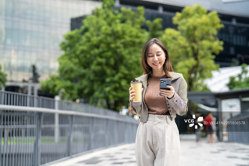 年轻专业人士在户外享受咖啡，同时浏览智能手机图片素材