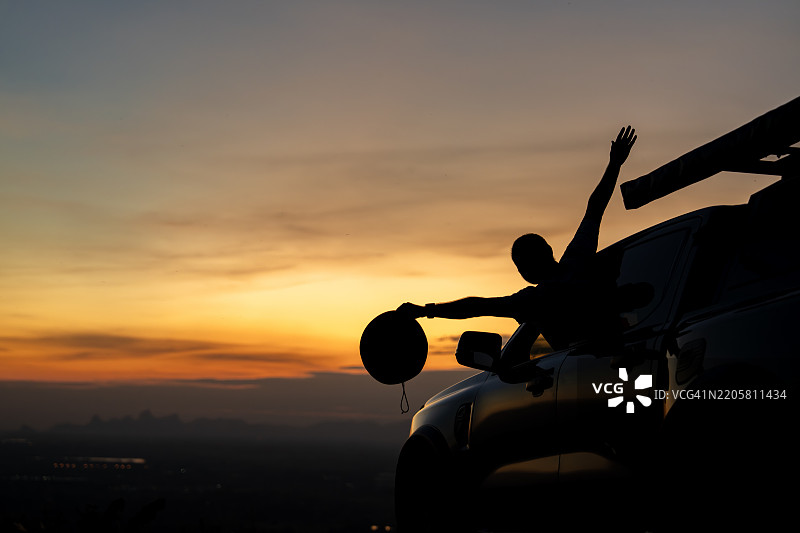 男子在风景如画的乡村中从车窗欣赏日落图片素材