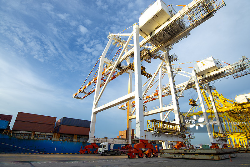 港口起重机与正在进行货物作业的集装箱船。图片素材