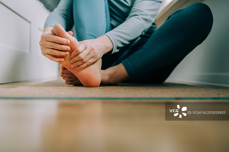 女人在瑜伽垫上按摩自己的脚图片素材