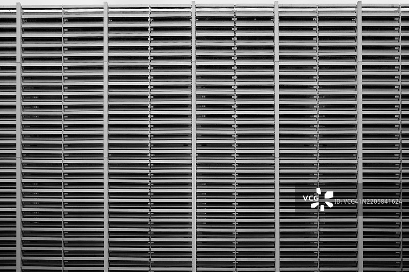 一个紧密裁剪的对称视角，展示了一个大型金属通风口或百叶窗系统。图片素材