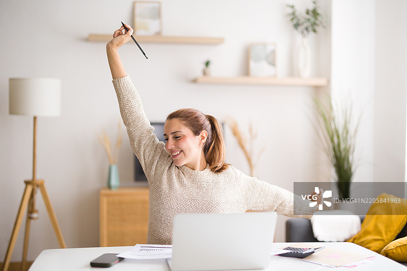 快乐的女人在家中支付完家庭账单后伸展身体图片素材