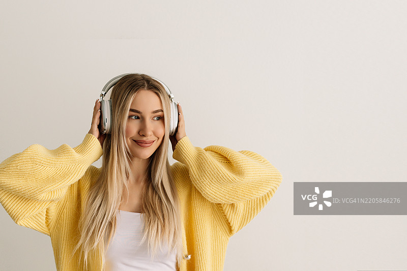 音乐、舞蹈和自由，背景为白色的女性形象，适用于市场营销或广告。微笑的年轻男子佩戴耳机，享受音乐或收听歌曲，旁边留有空白空间。图片素材