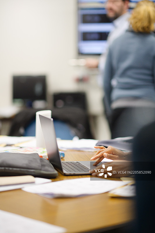 在繁忙的办公室互动中，手在笔记本电脑上打字图片素材