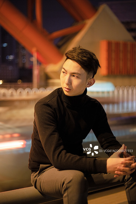 夜晚，一位伤心的亚洲男子站在街上图片素材