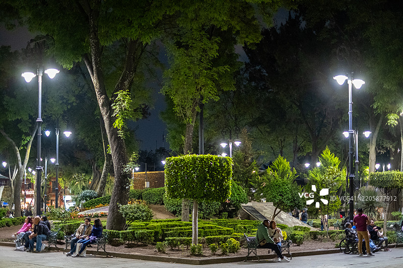 人们在墨西哥城科约阿坎时尚社区的伊达尔戈广场夜晚悠闲地放松。图片素材