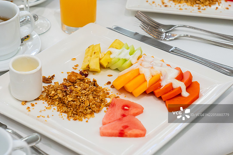 丰盛的水果早餐，包括格兰诺拉麦片、酸奶、木瓜、西瓜、哈密瓜、蜜瓜、苋菜和橙汁图片素材