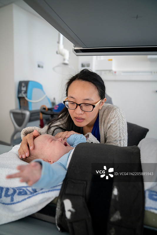 一位母亲在检查台上照顾她生病的孩子图片素材