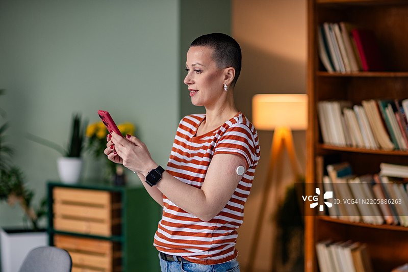年轻女性在舒适的居住空间中使用科技管理1型糖尿病，同时检查她的健康状况图片素材