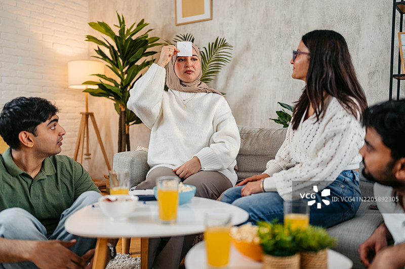 一群印度和穆斯林朋友在沙发上一起玩猜词游戏图片素材