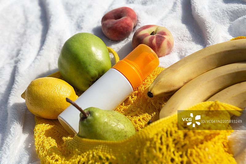 美丽的海滩野餐，篮子里的水果和旁边的防晒霜。安全的晒黑和夏季概念。图片素材