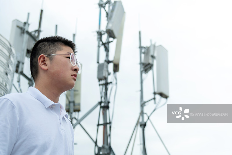 少年站在5G通信塔旁边图片素材