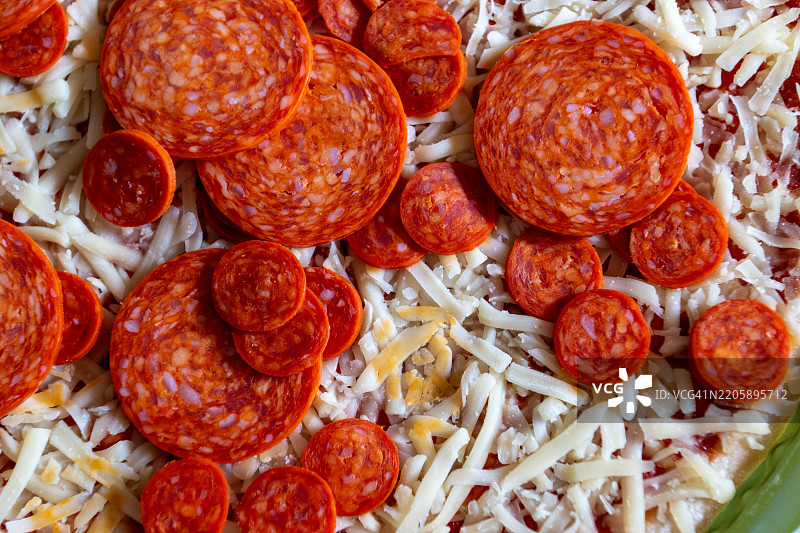 准备自制的意大利香肠披萨，配上磨碎的马苏里拉奶酪图片素材