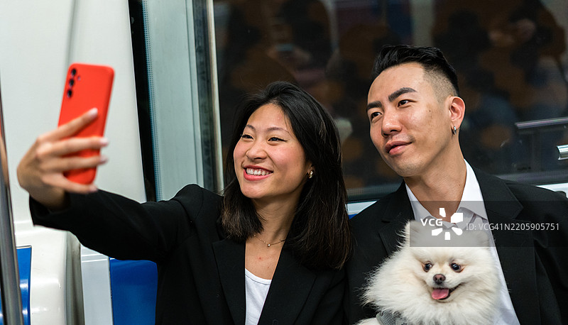 年轻情侣在地铁上与狗自拍图片素材