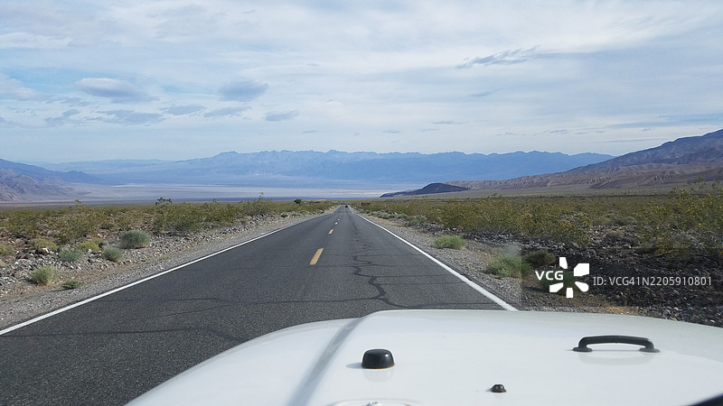 在日落前驾驶白色SUV行驶在荒凉的公路上图片素材