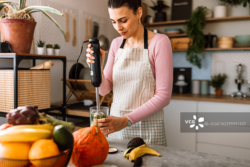 一位女性正在搅拌机中准备健康的排毒饮品图片素材