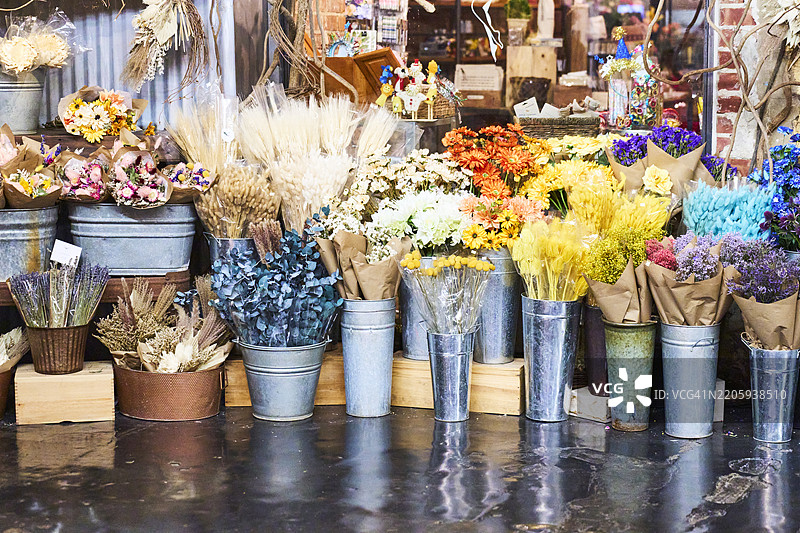 色彩缤纷的花店展示着新鲜和干燥的花朵，放在金属桶里图片素材