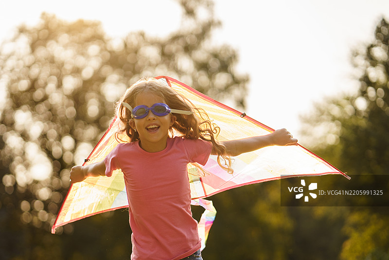 无忧无虑的女孩在户外玩风筝，假装自己在飞翔图片素材