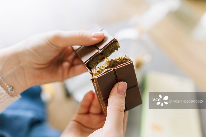 特写镜头：女人的手在撕开迪拜开心果巧克力棒图片素材