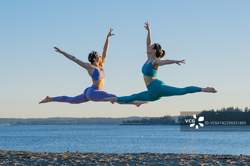 两位女性在海滩上优雅地跳着芭蕾舞，背景是风景如画的海洋，地点：华盛顿州贝恩布里奇岛的莱特尔海滩。图片素材
