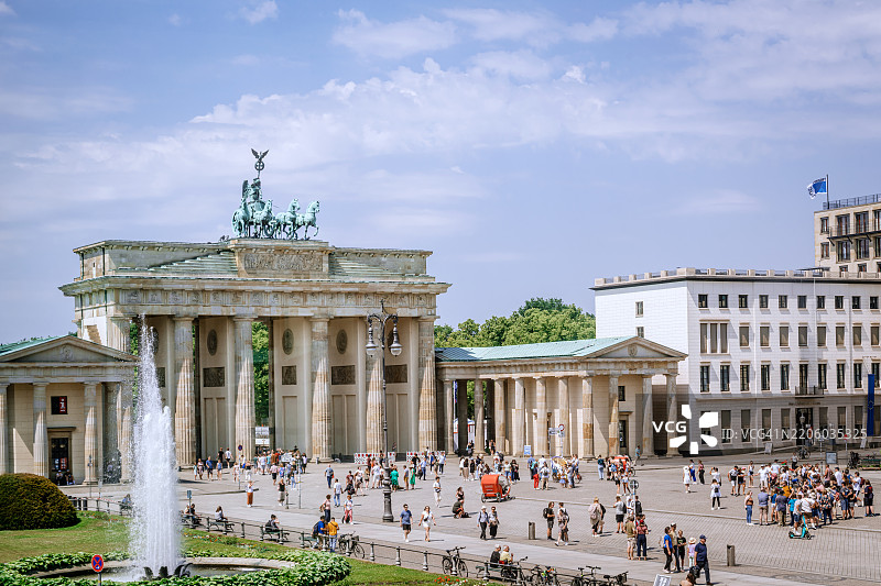 阳光明媚的日子里，游客围绕在德国柏林的勃兰登堡门周围图片素材